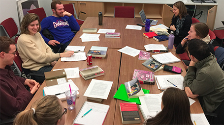 Instructor and students seated around a classroom table